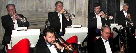 Four trumpets stand in the back row, while two trombones sit in front.