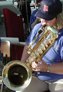 The camera looks down into the large bell of the bass sax, with the tall upper key stack at the right.