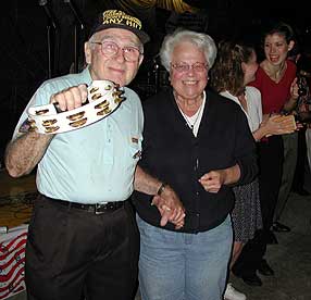 A guest percussionist shakes the tambourine at the camera while his wife smiles.