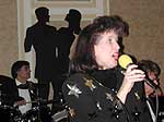 Karen sings "Skylark" with oversized cutouts of dancers near the wall behind her.