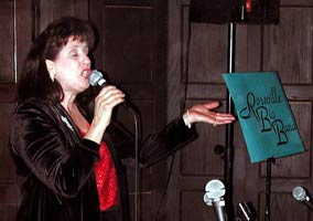 Singing with closed eyes, Karen gestures toward the Roseville big Band sign.
