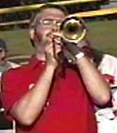 Glen plays a soprano trombone in a concert in Roseville's Central Park, facing the viewer.