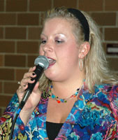Laura holds the microphone while singing.