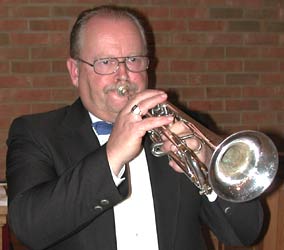 Harvey plays trumpet in front of the sanctuary's brick wall.