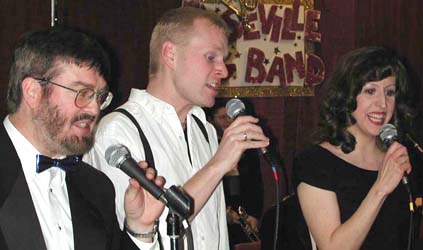 Glen, Tim, and Sara hold microphones as they sing.