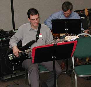 Tim plays in the foreground with John behind him.