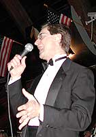 Reeves backs away from the microphone while gesturing with his left hand.