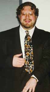 Andy wears a conservative suit and a colorful tie. Bigger picture is 30K.