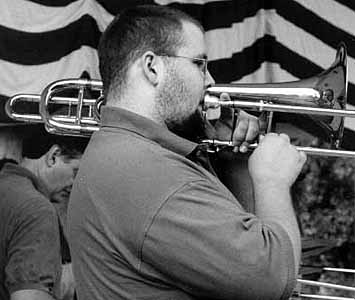Black-and-white photo of Jordan standing and playing, with a flag and other musicians in the background.