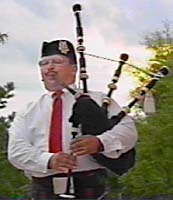 Lynn Ista, bagpiper, is silhouetted against the sky.