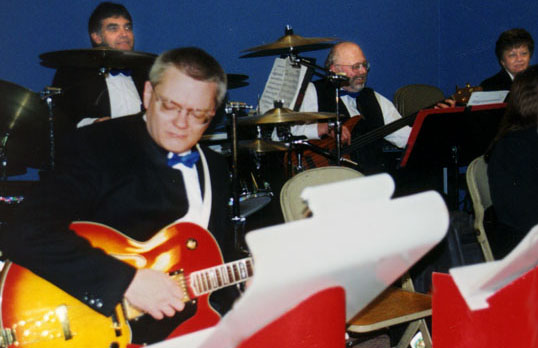 The quartet plays against a dark blue background.